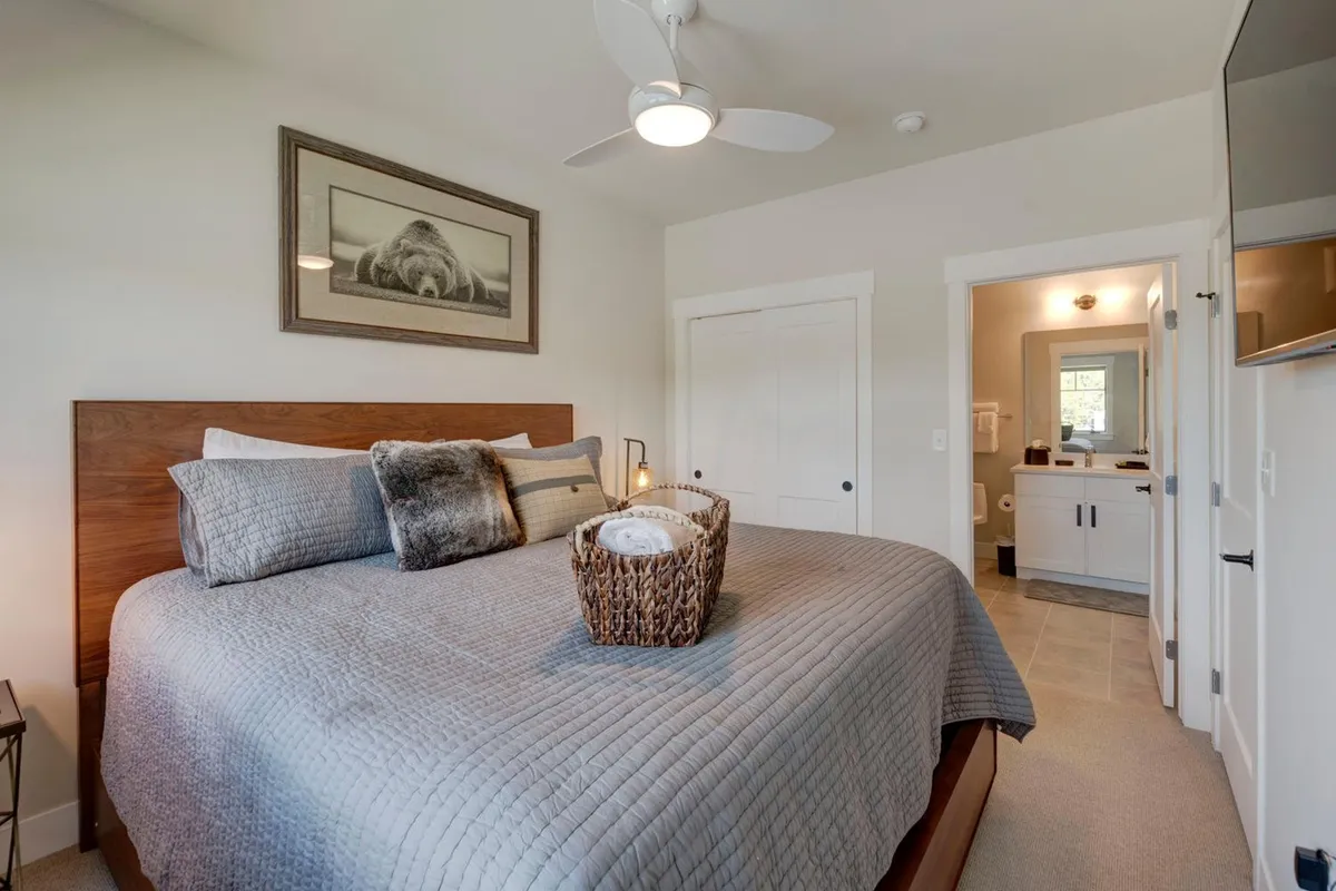 A calm bedroom featuring a bed with a textured quilt, a basket of fresh towels, and whimsical framed animal artwork. The gentle lighting and soft textures evoke a peaceful, family-friendly space ideal for relaxation.