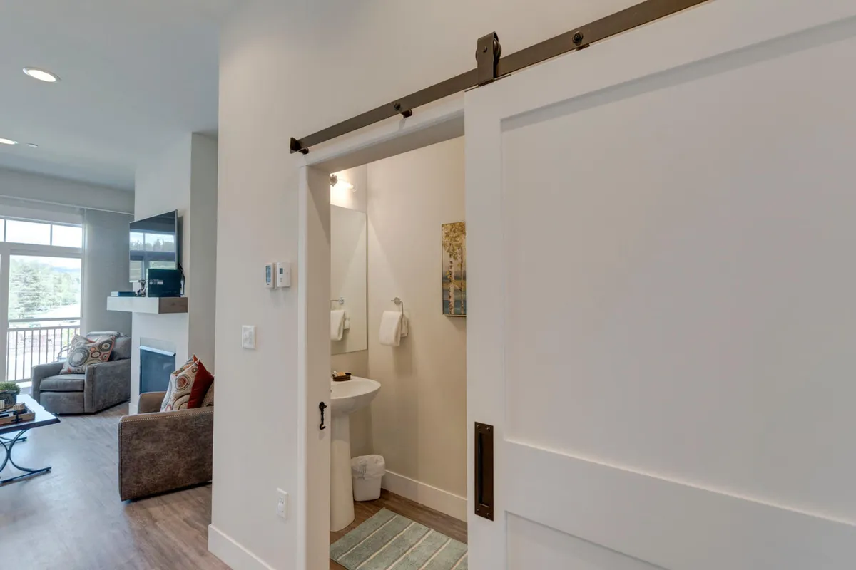 A cozy seating area with plush chairs facing a modern fireplace, highlighted by a sliding barn door and tasteful decorative art. The space emits a welcoming, relaxed vibe ideal for unwinding after a productive day, having casual conversations, or simply soaking in the ambience. The fireplace and open design suggest comfort and modern amenities.