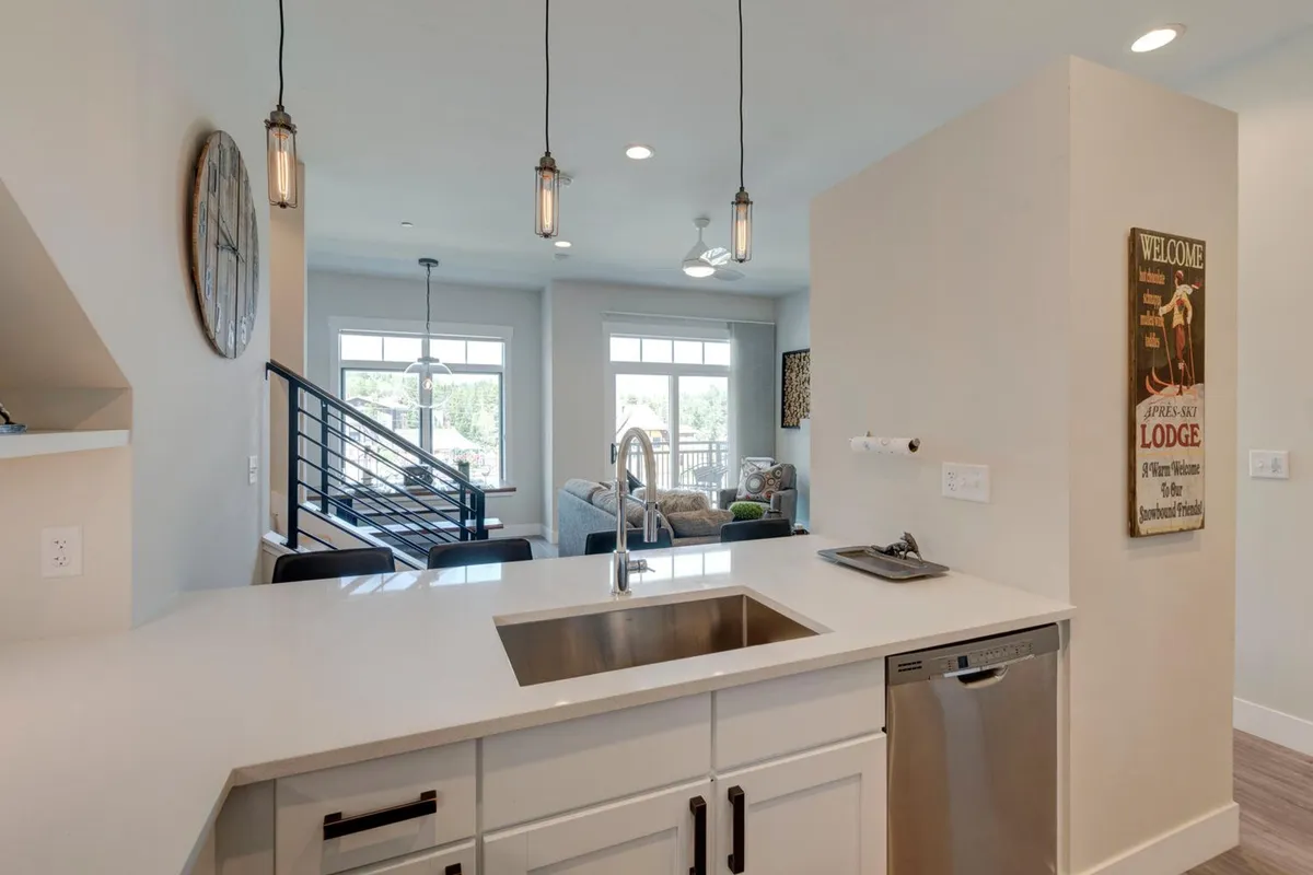 An open kitchen with a large island and integrated sink, pendant lights, and a seamless flow into the adjacent living area. The design encourages both cooking and social interaction, with plenty of natural light and modern finishes.