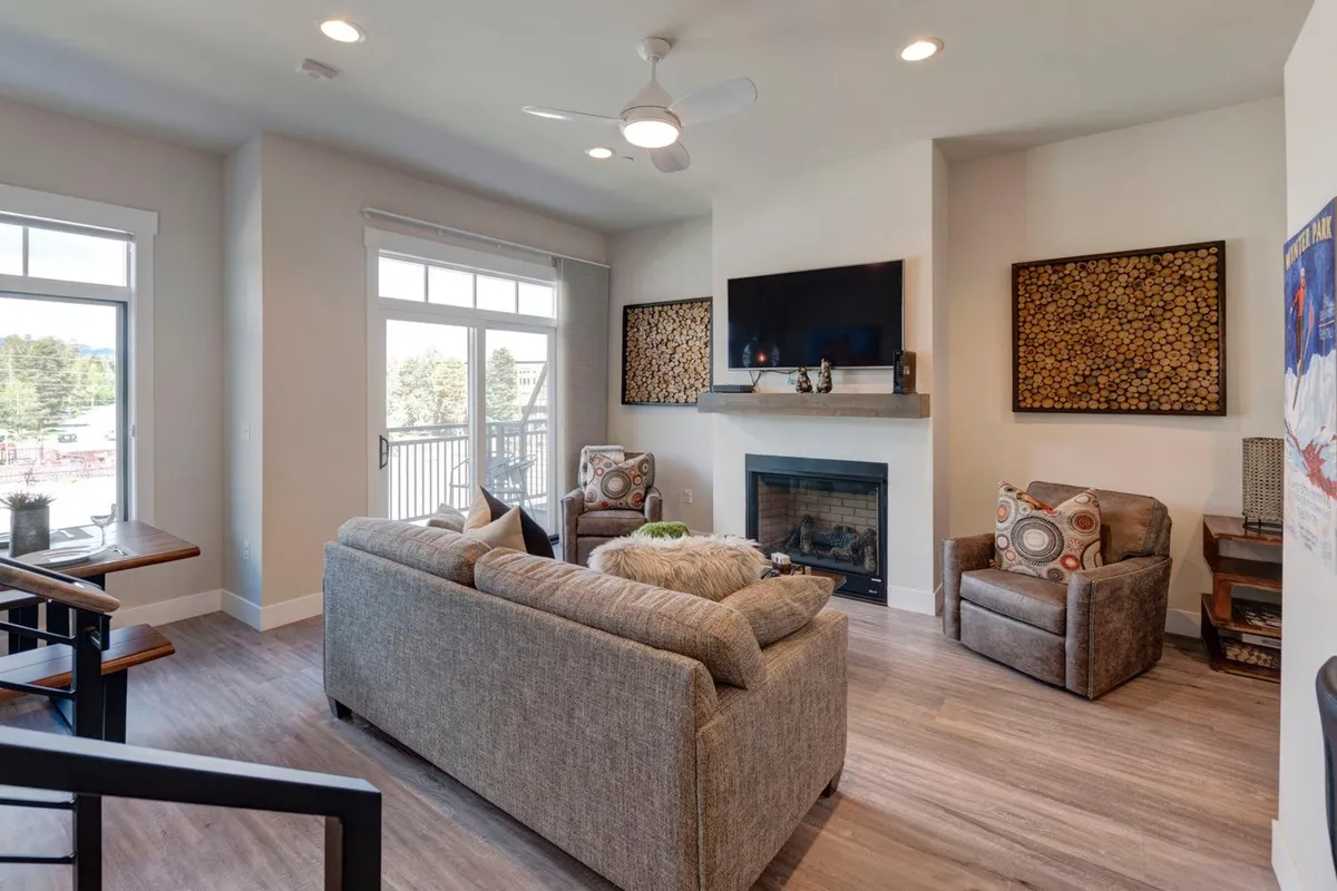 A living room scene with a comfortable sofa, modern fireplace, wall-mounted TV, and stylish decorative wall art. The setup encourages lounging and togetherness, with an inviting ambiance for movie nights or playing board games.